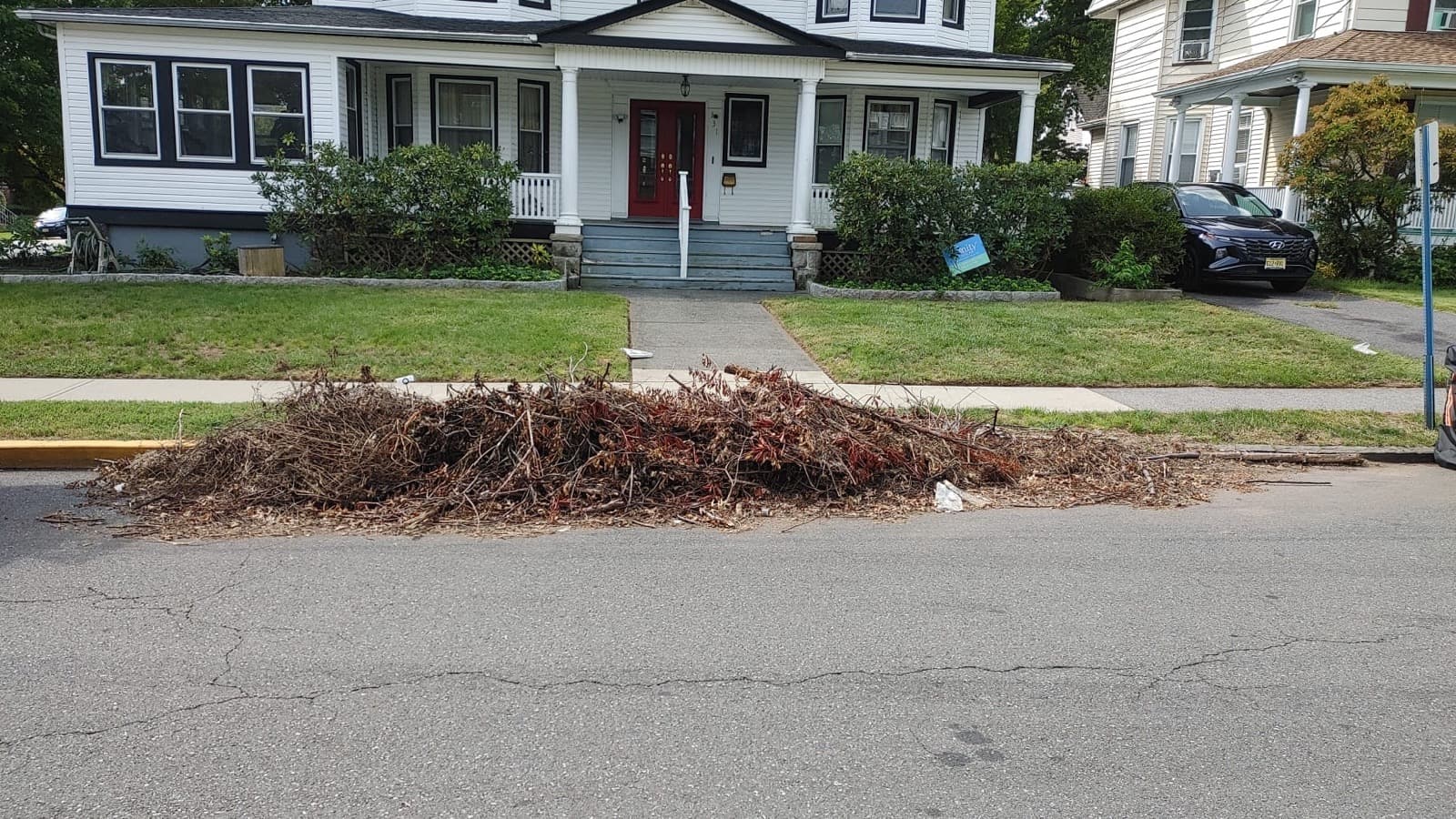 A large pile of storm brush and branches blocking the curb before removal.