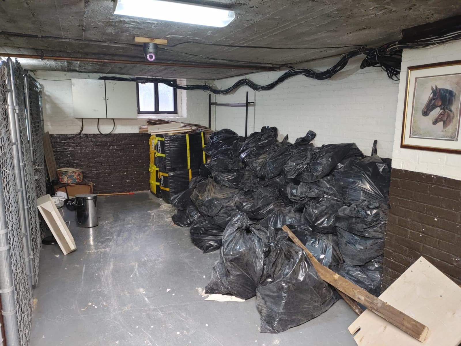 The same basement with debris bagged into a neat pile and the floor swept clear.